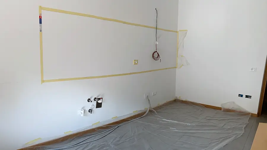 Leere Wohnung mit Malerkrepp an der Wand und Malerfolie auf dem Boden